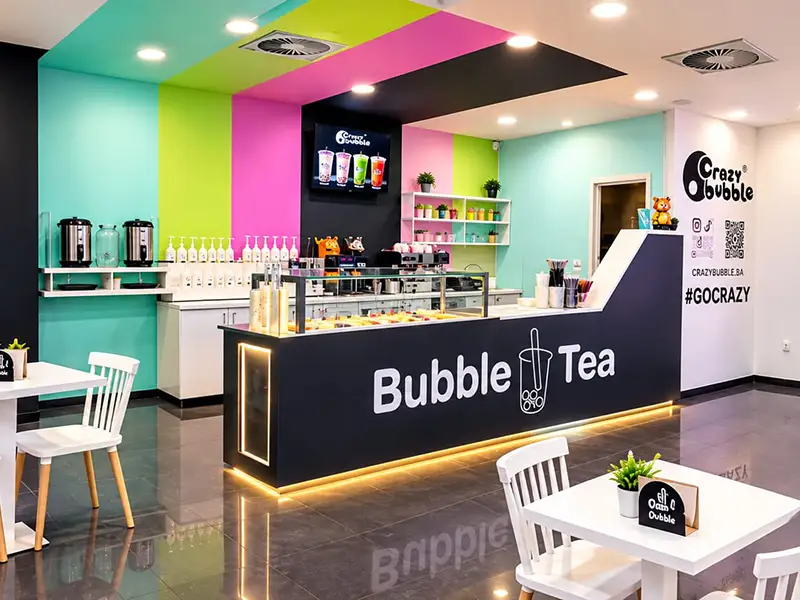 Bright bubble tea shop interior with teal, pink, and lime walls, a dark counter labeled 'Bubble Tea' and seating nearby.