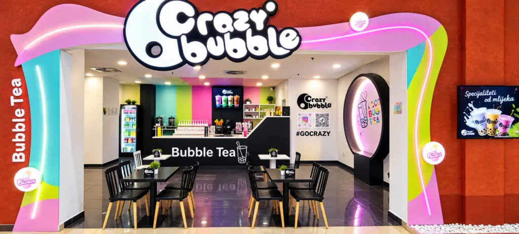 Exterior view of Crazy Bubble Bubble Tea shop with bright pink, teal, and lime accents and a large sign above the doorway