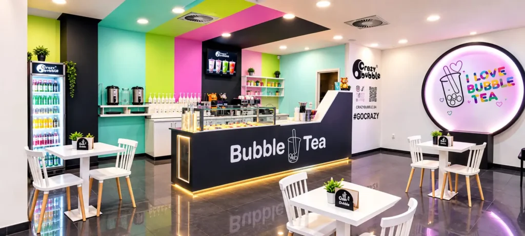 Bright bubble tea shop interior with colorful pastel walls, a dark front counter labeled 'Bubble Tea', and white tables and chairs.