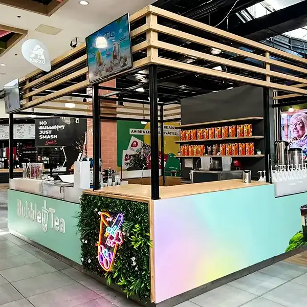 Bubble Tea kiosk in a shopping mall with a pastel gradient counter, wooden-frame canopy, and a neon bubble tea sign.