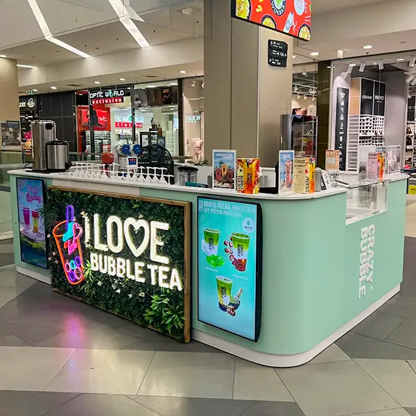 Bubble tea kiosk in a mall with a bright 'I Love Bubble Tea' sign and drink images on screens near the counter.