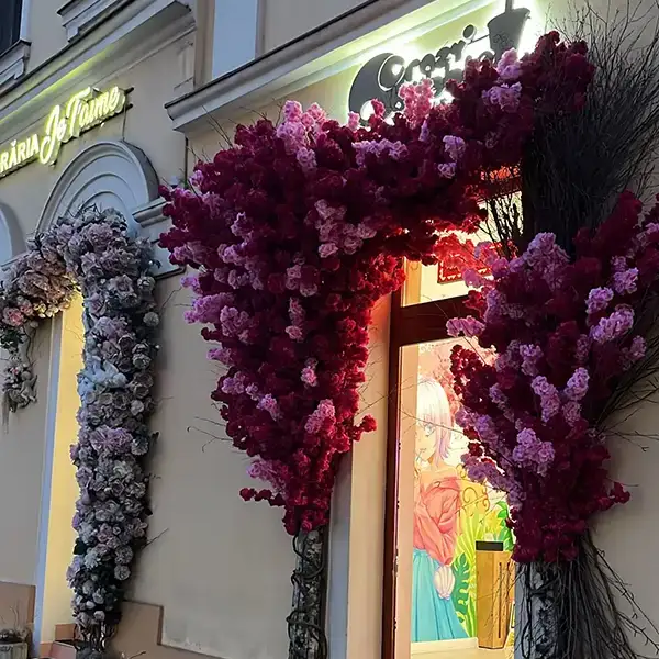 Storefront entrance decorated with vibrant pink and purple flower arches framing the doorway, creating a colorful display.